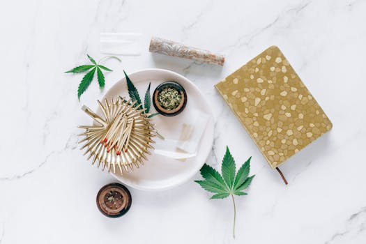 Feuilles de cannabis et accessoires soigneusement disposés sur un plan de travail en marbre, illustrant un concept de style de vie.