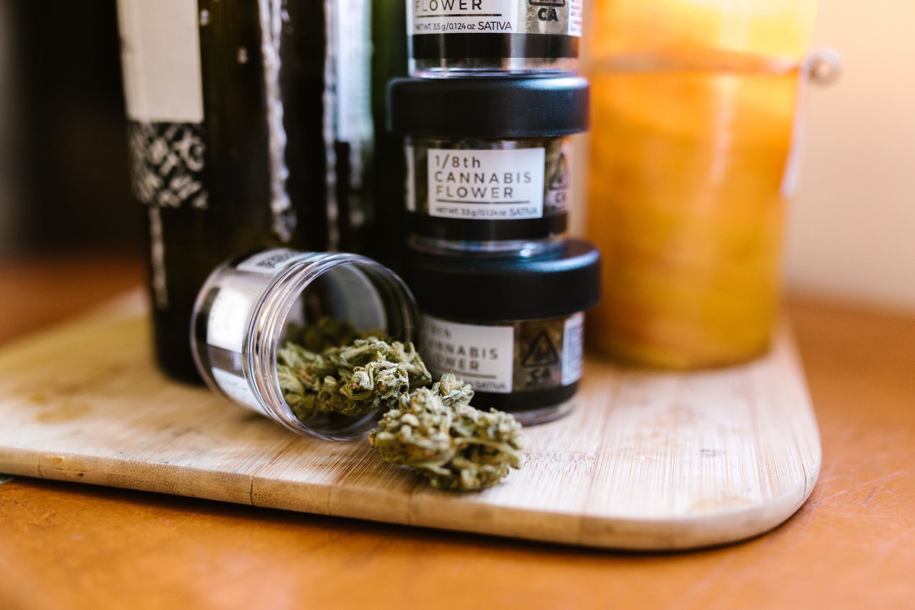 Bourgeons de cannabis dans des bocaux en verre sur une planche en bois en intérieur avec un éclairage doux.