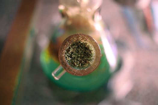 Image détaillée de cannabis moulu tassé dans une pipe en verre, mettant en valeur sa texture complexe.